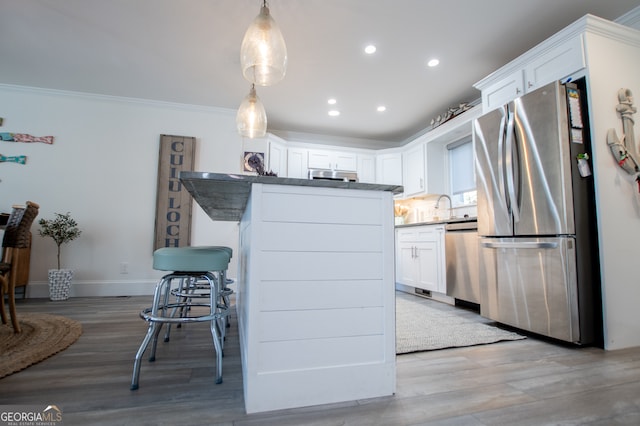 kitchen with white cabinetry, light hardwood / wood-style flooring, appliances with stainless steel finishes, and decorative light fixtures