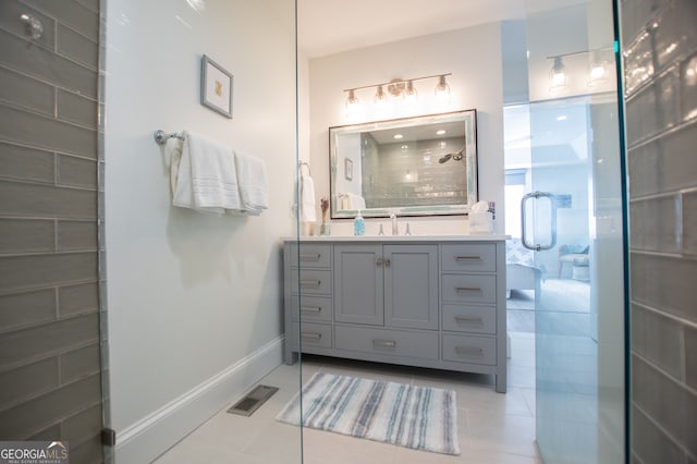 bathroom with a shower with door, vanity, and tile patterned flooring