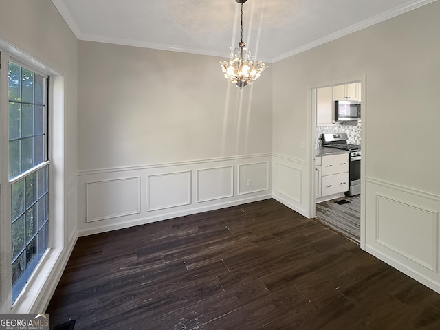 unfurnished dining area with a chandelier, dark wood-style floors, crown molding, wainscoting, and a decorative wall