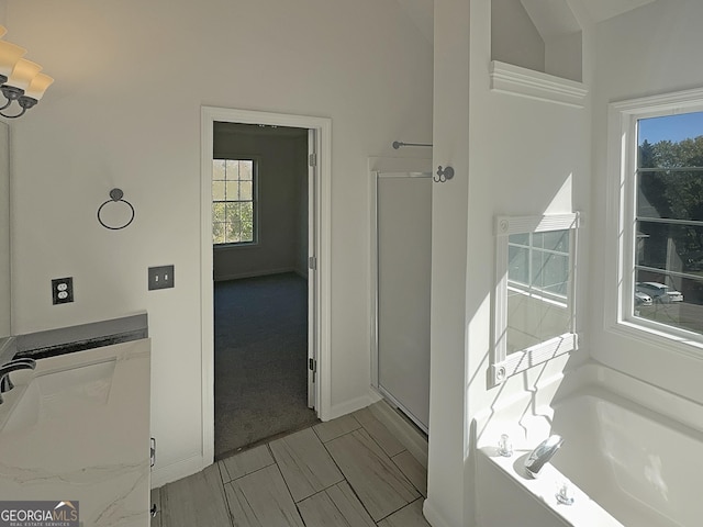 bathroom with a stall shower, a bath, lofted ceiling, and baseboards