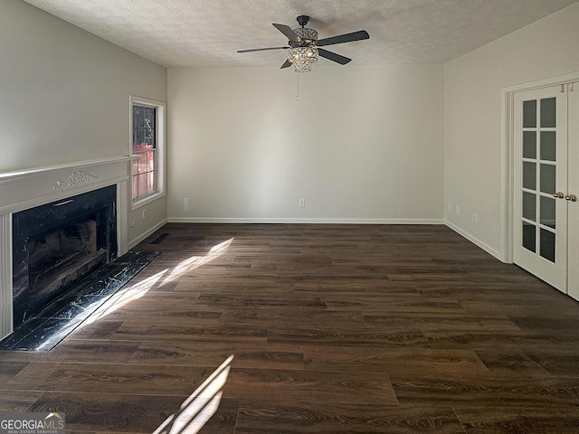 unfurnished living room featuring dark wood-style flooring, a premium fireplace, a textured ceiling, a ceiling fan, and baseboards
