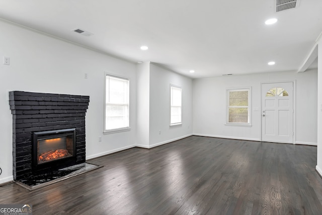 unfurnished living room with crown molding, a brick fireplace, and dark hardwood / wood-style floors