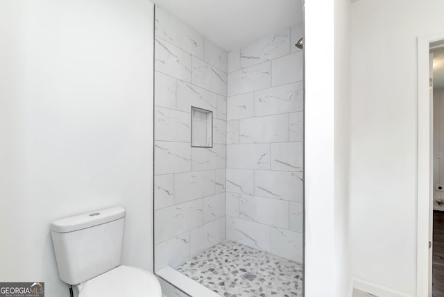 bathroom featuring toilet and tiled shower