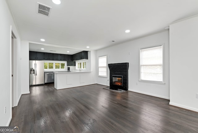 unfurnished living room featuring ornamental molding, a healthy amount of sunlight, and dark hardwood / wood-style flooring