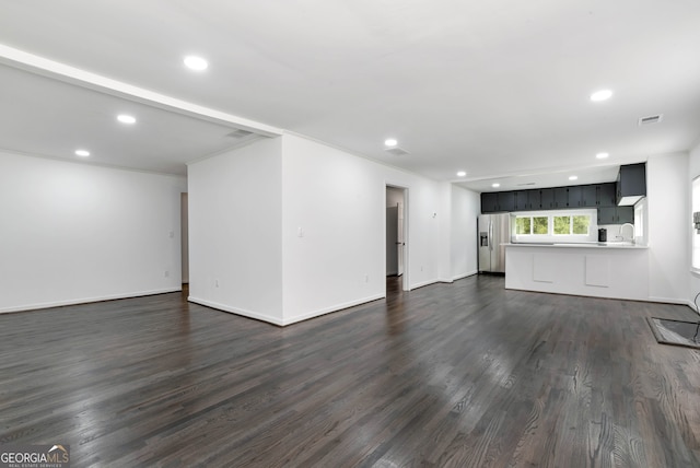 unfurnished living room with dark wood-type flooring, ornamental molding, and sink