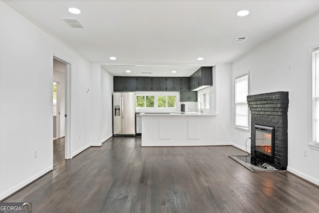 unfurnished living room with dark wood-type flooring, ornamental molding, sink, and a brick fireplace