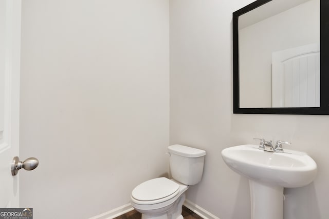 bathroom featuring toilet, sink, and wood-type flooring