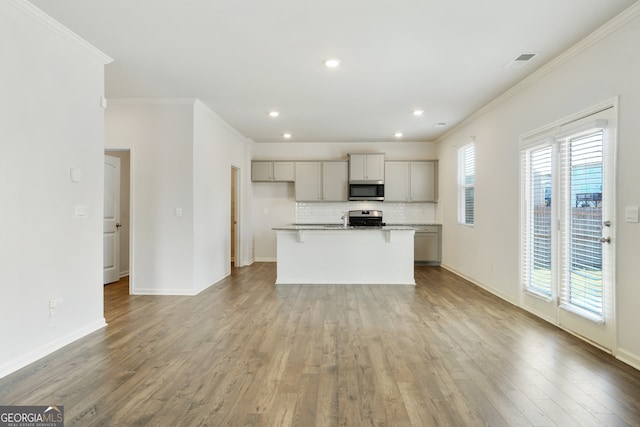 kitchen with appliances with stainless steel finishes, a kitchen island with sink, a healthy amount of sunlight, and gray cabinets