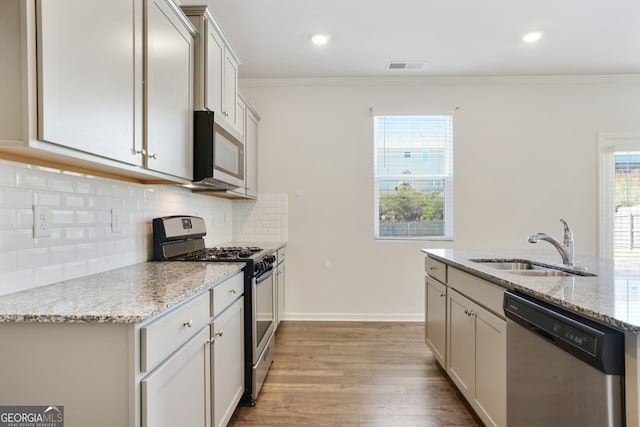 kitchen with light hardwood / wood-style flooring, sink, light stone countertops, crown molding, and appliances with stainless steel finishes