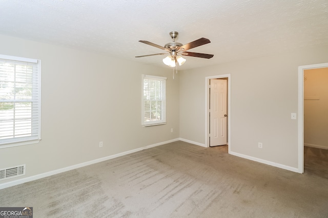 carpeted spare room featuring a textured ceiling and ceiling fan