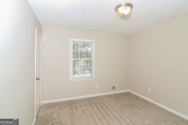 spare room with a textured ceiling and light colored carpet