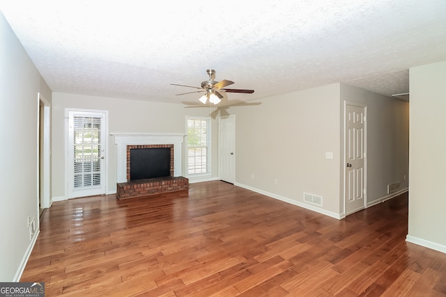 unfurnished living room featuring a healthy amount of sunlight, a textured ceiling, and hardwood / wood-style floors