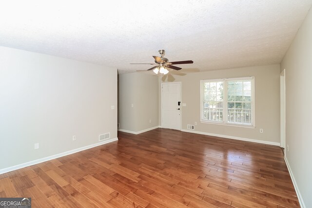 empty room with a textured ceiling, hardwood / wood-style flooring, and ceiling fan