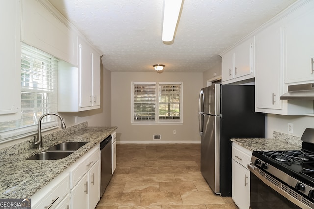 kitchen featuring white cabinets, exhaust hood, appliances with stainless steel finishes, a textured ceiling, and sink