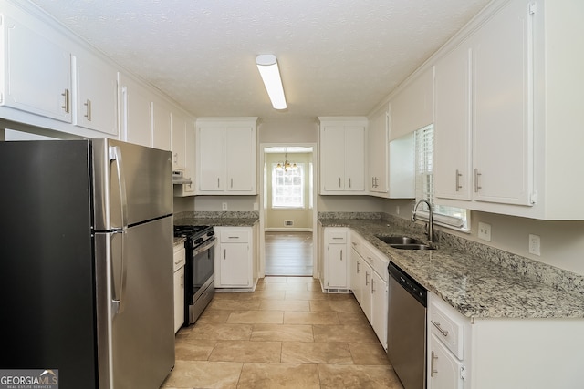 kitchen with white cabinets, a textured ceiling, dark stone countertops, sink, and stainless steel appliances