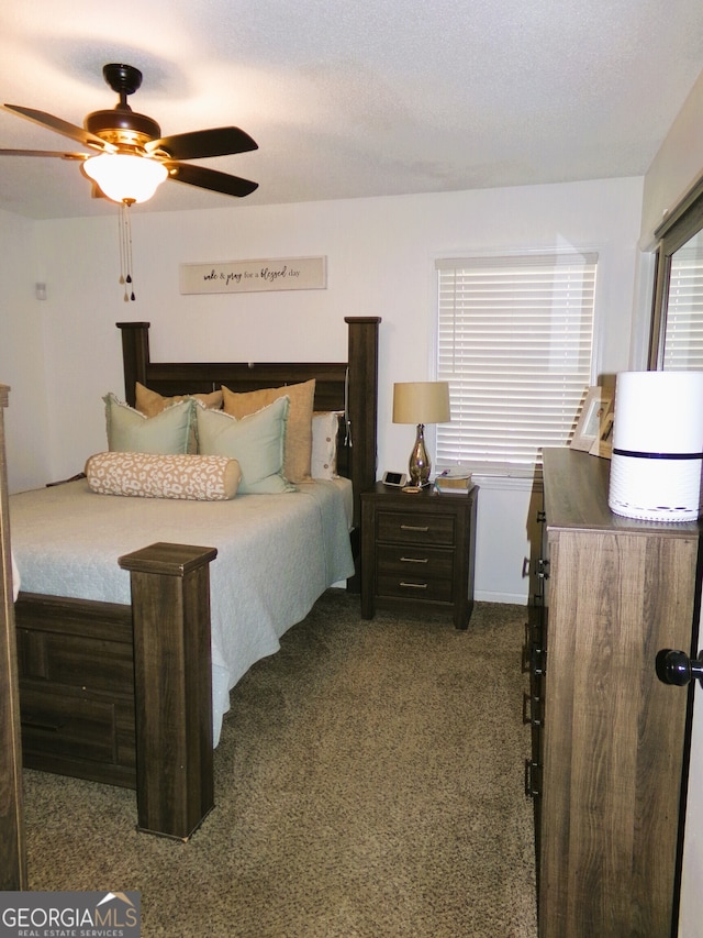 bedroom with ceiling fan, a textured ceiling, and dark colored carpet