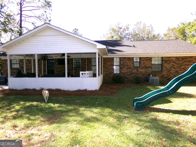 back of property with a playground, central AC, and a lawn