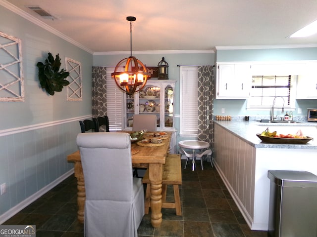 dining area featuring a notable chandelier, sink, and crown molding