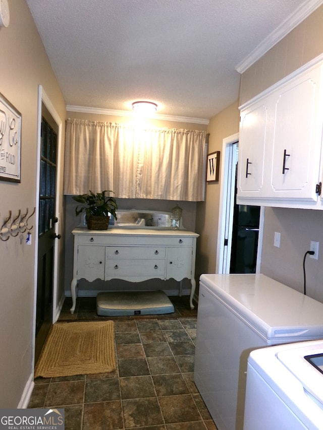 laundry area featuring washer / dryer, crown molding, a textured ceiling, and cabinets