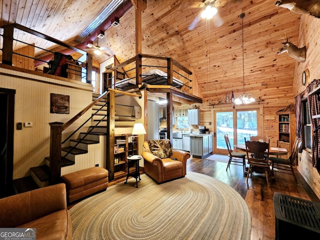 living room with ceiling fan with notable chandelier, wood ceiling, wooden walls, hardwood / wood-style flooring, and high vaulted ceiling