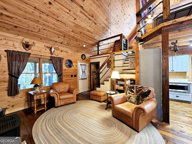 living room featuring high vaulted ceiling, hardwood / wood-style floors, and wooden walls