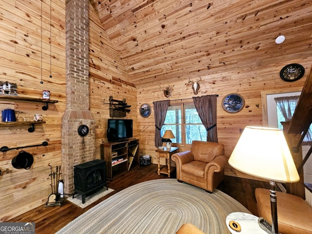 living room with a wood stove, hardwood / wood-style flooring, wooden walls, and high vaulted ceiling