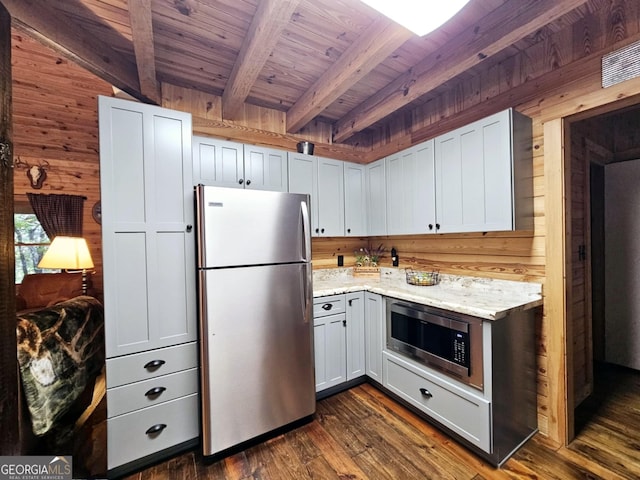 kitchen with stainless steel appliances, wood walls, dark hardwood / wood-style floors, beamed ceiling, and white cabinetry