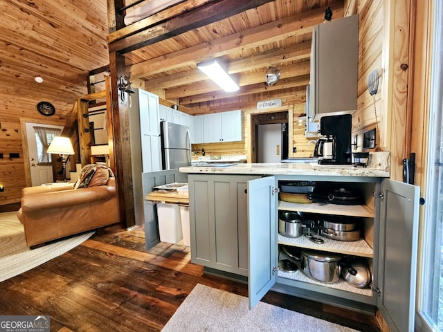 kitchen featuring wood walls, beamed ceiling, stainless steel fridge, and dark hardwood / wood-style floors