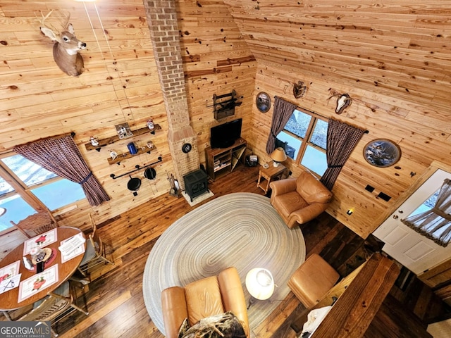 living room featuring a towering ceiling, wood walls, and wood-type flooring