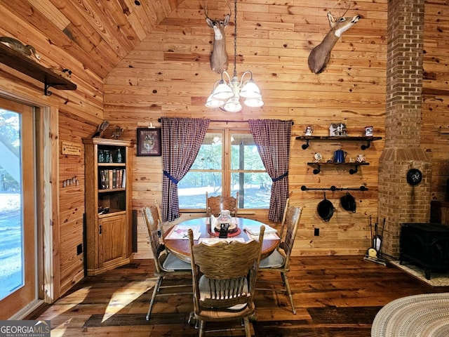 dining space with dark wood-type flooring, wood walls, vaulted ceiling, and a notable chandelier