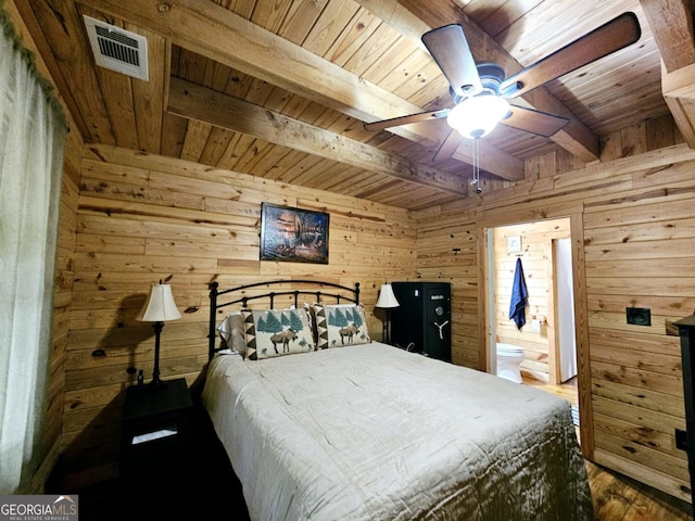 bedroom with connected bathroom, wooden walls, beamed ceiling, wooden ceiling, and ceiling fan