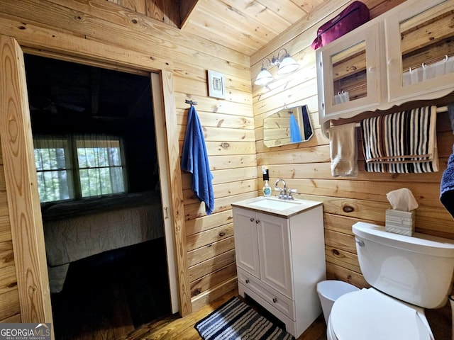 bathroom featuring wood walls, hardwood / wood-style flooring, wooden ceiling, vanity, and toilet