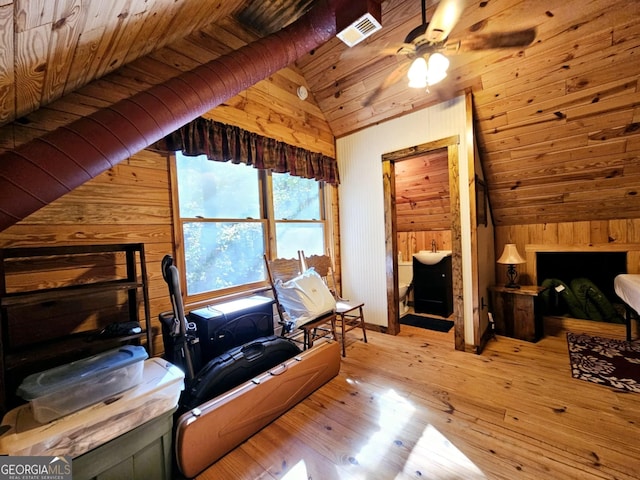 interior space featuring wood walls, light wood-type flooring, and vaulted ceiling