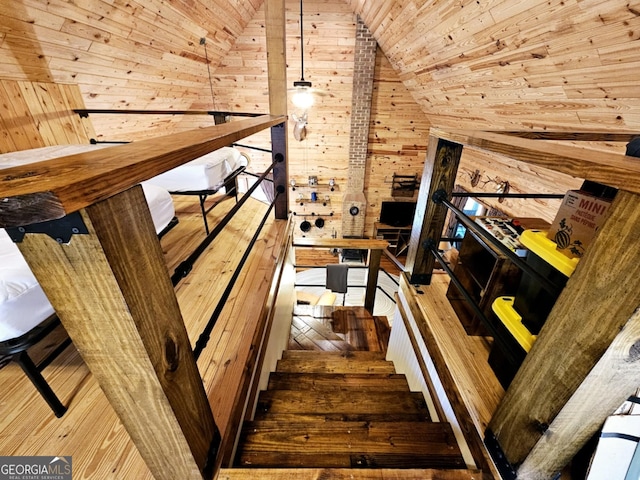 staircase featuring wood-type flooring, wooden walls, wood ceiling, and lofted ceiling