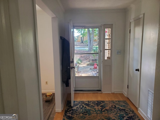 entryway featuring ornamental molding and light hardwood / wood-style flooring