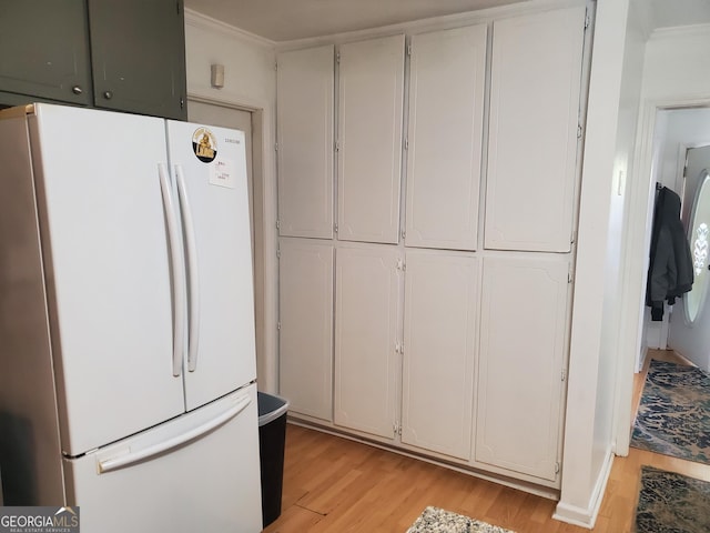 kitchen with white refrigerator, light hardwood / wood-style floors, white cabinetry, and ornamental molding