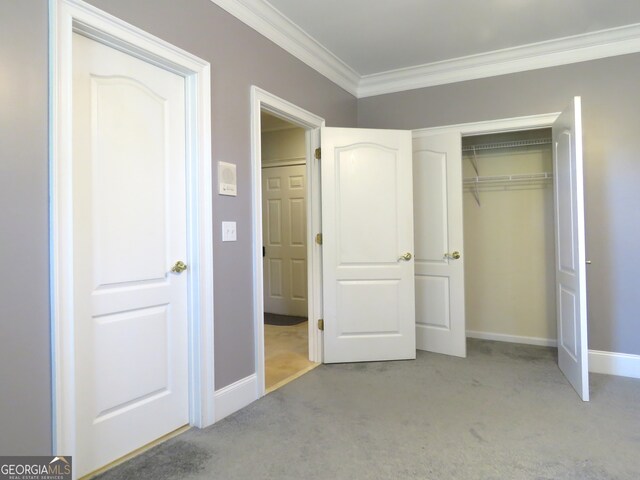 unfurnished bedroom featuring crown molding, light carpet, and a closet