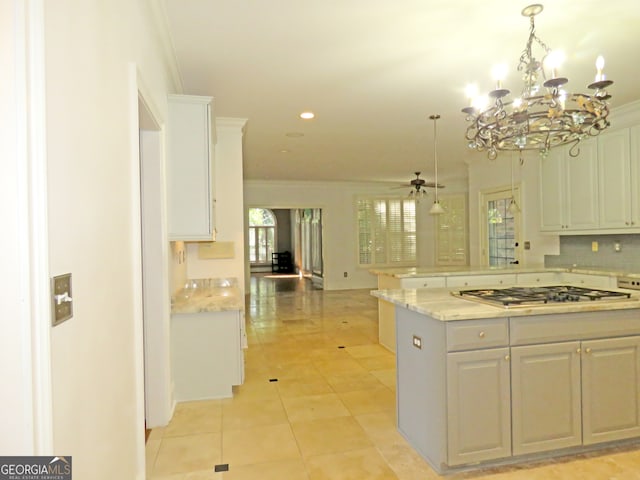 kitchen featuring light stone countertops, ceiling fan with notable chandelier, hanging light fixtures, white cabinetry, and stainless steel gas stovetop