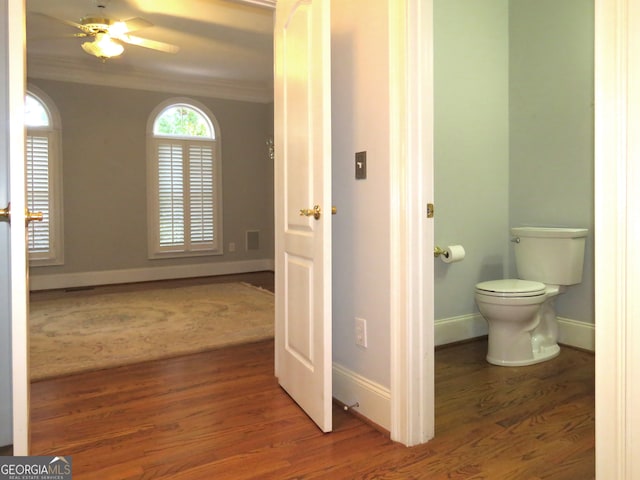 bathroom featuring toilet, hardwood / wood-style floors, ceiling fan, and ornamental molding