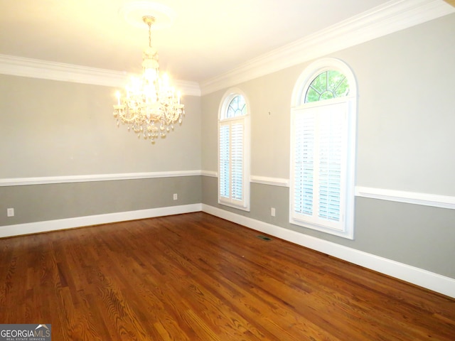 spare room with a notable chandelier, ornamental molding, and hardwood / wood-style flooring