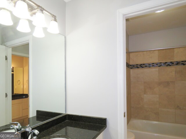 full bathroom featuring vanity, tiled shower / bath combo, and toilet