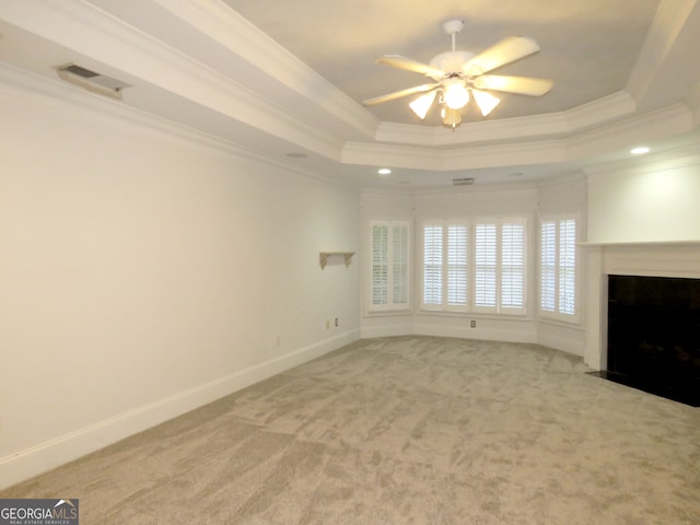 unfurnished living room featuring ornamental molding, carpet floors, a tray ceiling, and ceiling fan