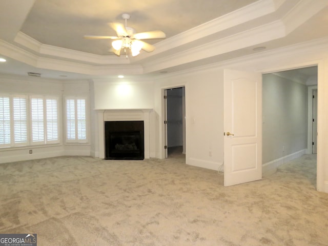 unfurnished living room featuring crown molding, a raised ceiling, light carpet, and ceiling fan