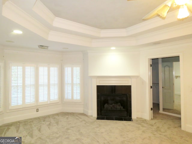 unfurnished living room featuring ornamental molding, light carpet, a tile fireplace, and a raised ceiling