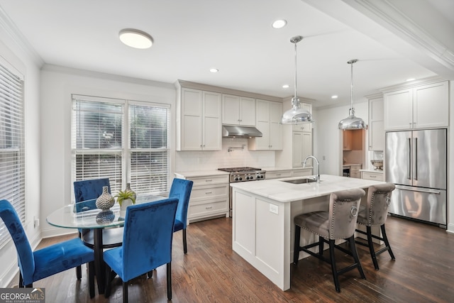 kitchen featuring dark wood-type flooring, an island with sink, hanging light fixtures, stainless steel appliances, and sink