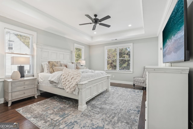 bedroom with ornamental molding, dark wood-type flooring, a raised ceiling, and ceiling fan