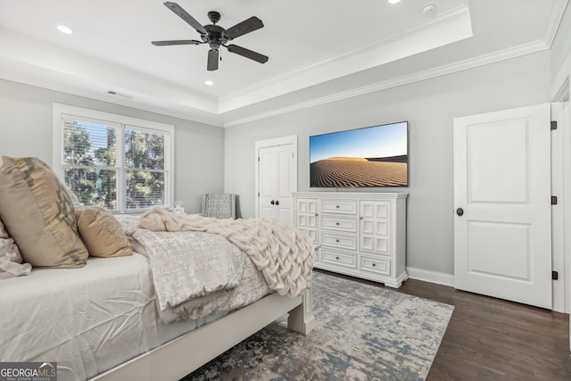 bedroom with crown molding, dark hardwood / wood-style floors, a tray ceiling, and ceiling fan