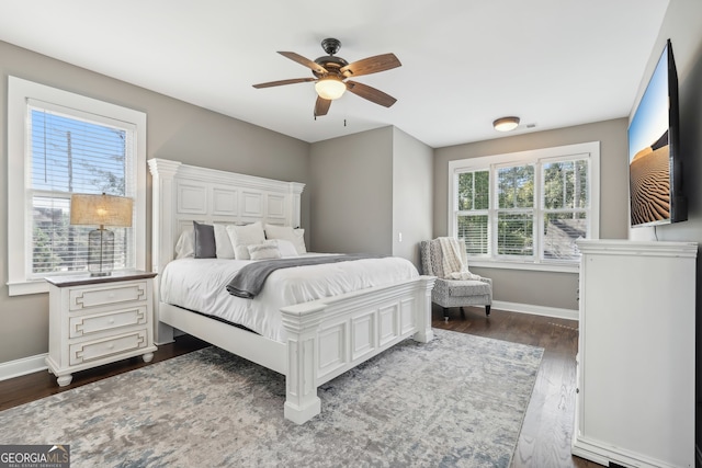 bedroom featuring multiple windows, dark wood-type flooring, and ceiling fan