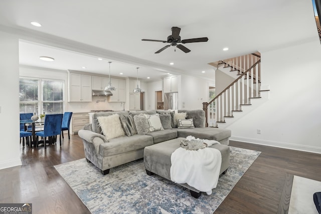 living room with dark wood-type flooring, ceiling fan, and ornamental molding