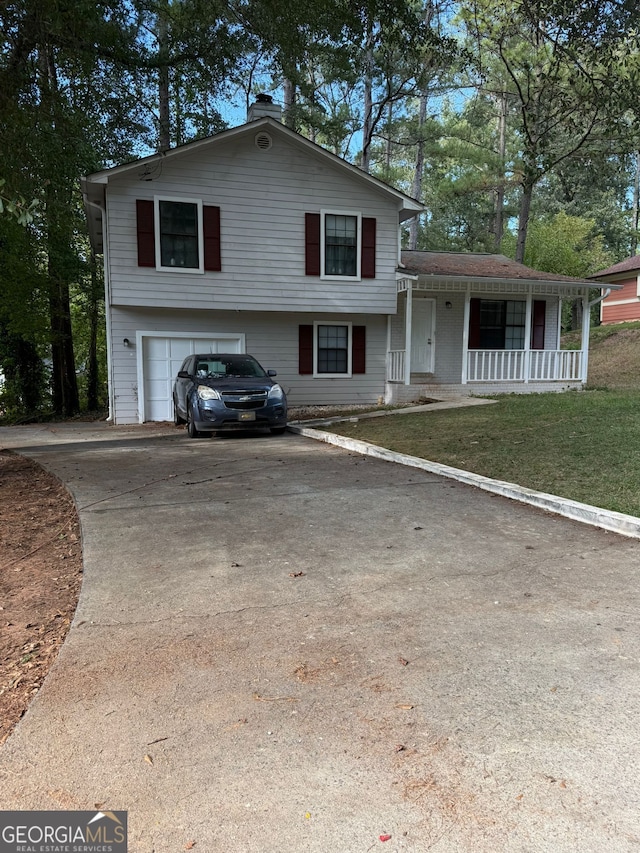 split level home featuring a porch, a front lawn, and a garage